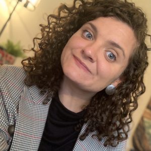 A selfie of a white woman with curly brown hair wearing a blazer.